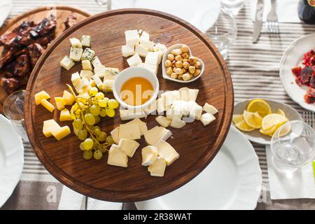 Käseplatte mit Haselnüssen, Honig, Trauben auf hölzernen Tisch Stockfoto