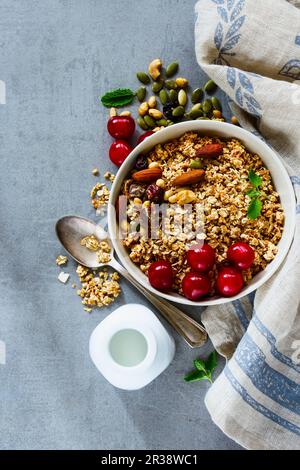 Leckeres Müsli, Nüsse und Beeren, Müsli mit frischen Kirschen, Minze und Milch oder Joghurt Stockfoto