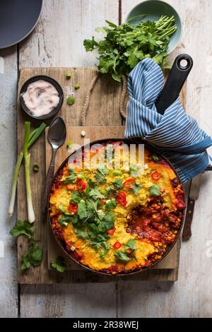 Vegane Torte mit Tomaten, roten Nierenbohnen, Mais gewürzt mit geräuchertem Paprika und Kreuzkümmel und gekrönt mit Polenta, Frühlingszwiebeln, Chili und Koriander Stockfoto