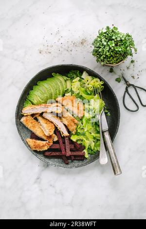 Wiener Eskalope mit roten Polenta-Chips, Avocado und Salat mit Rettich-Keimlingen Stockfoto