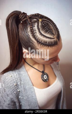 Cornrows-Frisur für ein Mädchen mit dunklen Haaren und dünnen Zöpfen, die an einen Schwanz gebunden sind Stockfoto