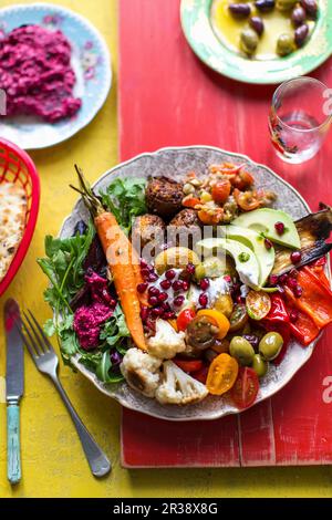 Hummus aus Rote Bete, Falafel, Fladenbrot, Mezze, Mutabal, Oliven, Paprika, Pommigranet, gebratene Karotten, gebratener Blumenkohl, Bratkartoffeln, Salat Stockfoto