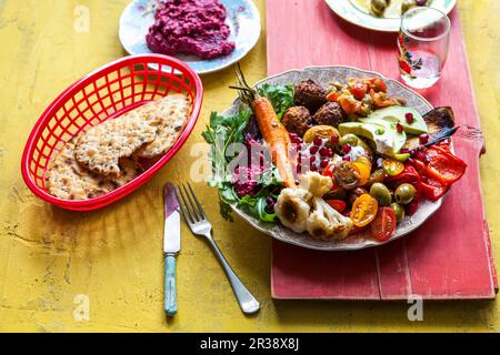 Hummus aus Rote Bete, Falafel, Fladenbrot, Mezze, Mutabal, Oliven, Paprika, Pommigranet, gebratene Karotten, gebratener Blumenkohl, Bratkartoffeln, Salat Stockfoto