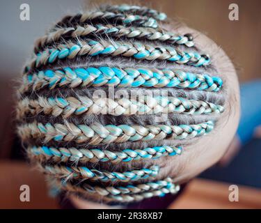 Eine Frau mit einem Haarschnitt auf einem weißen Hintergrund, engen Zöpfen geflochten in einem Schwanz, künstliches Material in ihr Haar gewebt Stockfoto