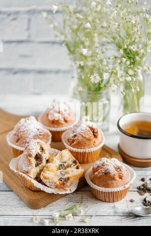 Muffins mit Schokolade und Puderzucker, serviert mit Tee Stockfoto