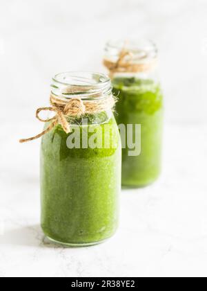 Zwei kleine Flaschen gesunder veganer grüner Smoothie, hergestellt aus Babyspinat und Grünkohl Stockfoto