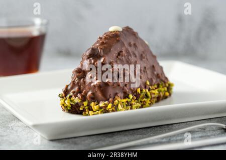 Dessertkuchen aus Malaga auf einem Steintisch. Kuchen mit Banane im Inneren, mit Schokoladensoße und Haselnüssen bedeckt Stockfoto