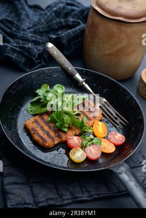 Gegrilltes veganes Hacksteak mit Tomaten und Salat in einer Pfanne Stockfoto