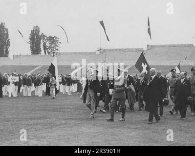 Olympische Spiele 1936 In Berlin. Die Olympischen Sommerspiele 1936 (deutsch: Olympische Sommerspiele 1936), offiziell bekannt als die Spiele der XI. Olympiade (deutsch: Spiele der XI Olympiade) und allgemein als Berlin 1936 bekannt, war eine internationale Multisport-Veranstaltung, die vom 1. Bis 16. August 1936 in Berlin stattfand. Das Olympiastadion in Berlin ist ein Stadion für die olympischen sommerspiele 1936 mit Platz für 100 000 Personen und der großen Eröffnung der olympischen Spiele am 1. august 1936. Adolf Hitler vor der Eröffnung mit Sportlern aus den verschiedenen Ländern im Hintergrund. Stockfoto