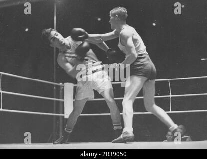 Olympische Spiele 1936 In Berlin. Die Olympischen Sommerspiele 1936 (deutsch: Olympische Sommerspiele 1936), offiziell bekannt als die Spiele der XI. Olympiade (deutsch: Spiele der XI Olympiade) und allgemein als Berlin 1936 bekannt, war eine internationale Multisport-Veranstaltung, die vom 1. Bis 16. August 1936 in Berlin stattfand. Der schwedische Leichtboxer Erik Ågren im Bronzeschlaftspiel überwindet den amerikanischen Boxer Scrivani. Stockfoto