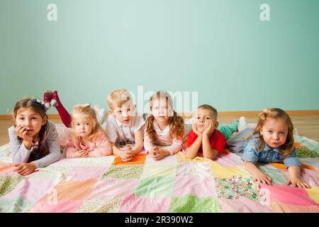 Gruppe von sechs Kindern, die zu Hause auf dem Boden lagen Stockfoto