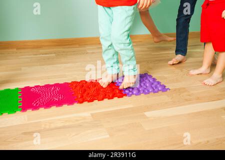 Nahaufnahme von Kinderfüßen im Stehen auf einer speziellen Massagematte Stockfoto