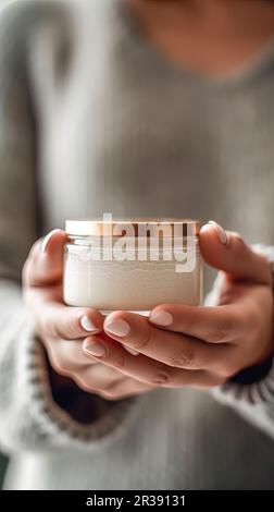 Eine junge Frau hält ein Glas frischer, natürlicher Hautpflegecreme Stockfoto