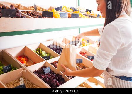 Die Frau packt getrocknete Aprikosen im Supermarkt ein Stockfoto