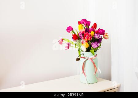 Strauß bunter Tulpen in weißer Dose Stockfoto