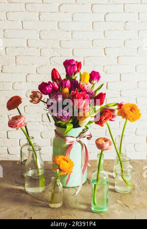 Ein Haufen Tulpen in der Dose. Butterbecher in Glasflaschen Stockfoto