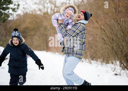 Die Tochter reitet mit ihrem Vater im Winterwald. Stockfoto