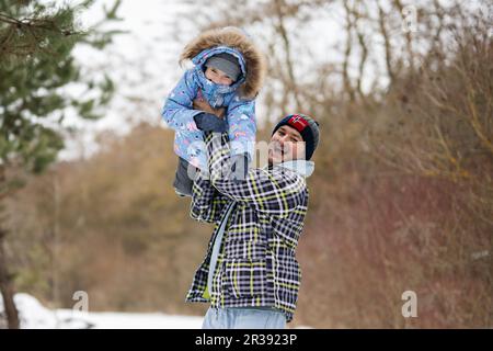 Die Tochter reitet mit ihrem Vater im Winterwald. Stockfoto