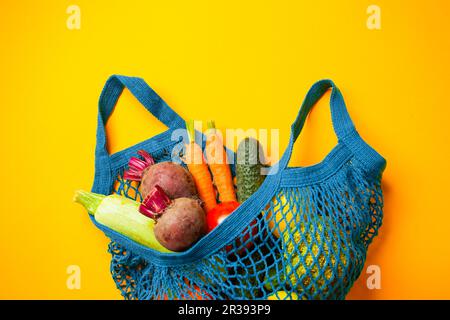 Gemüse in einem Baumwollbeutel mit Netzgewebe auf gelbem Hintergrund Stockfoto