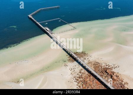 Aus der Vogelperspektive sehen Sie einen langen, schmalen Anleger, der sich in eine ruhige Küstenbucht an der Moonta Bay in Südaustralien erstreckt Stockfoto