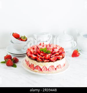 Erdbeerkuchen Fraisier auf dem weißen Teller und den Tassen Stockfoto