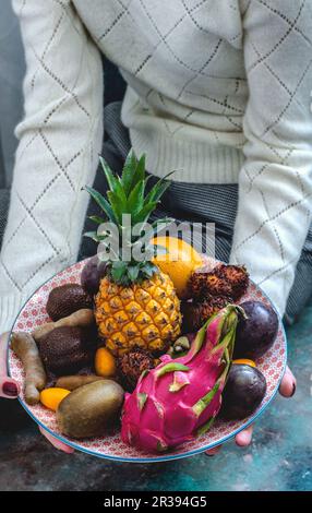 Exotische Früchte auf einem Teller in den Händen Stockfoto