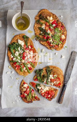 Socca-Pizza (Kichererbsenmehl-Pfannkuchen) mit Paprika, Tomaten, Brokkoli und Fetakäse Stockfoto