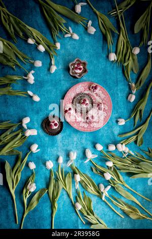 Rosa Kuchen mit Raspelbeeren und weißen Tulpen vor blauem Hintergrund Stockfoto