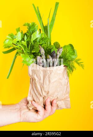 Spargel und Grün für Salat in einer Papiertüte in der Hand Stockfoto