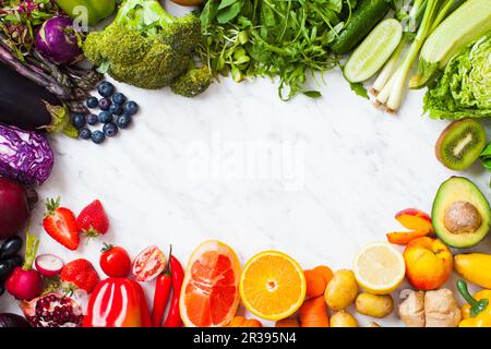 Regenbogenfarbenes Obst und Gemüse auf einem weißen Tisch Stockfoto