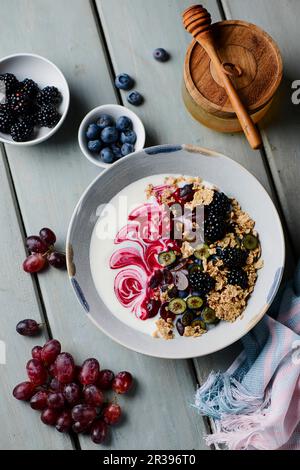 Eine Joghurtschale mit Vollkorn-Haferbrei, Beeren und Trauben Stockfoto