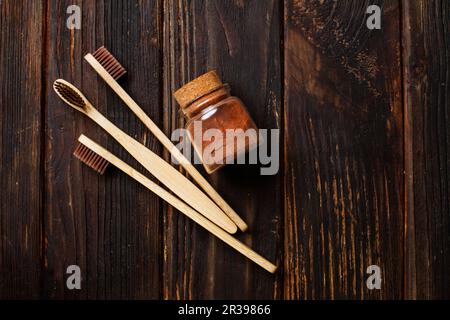 Nahaufnahme von drei Bambus Zahnbürsten und Zahnpasta Pulver Stockfoto