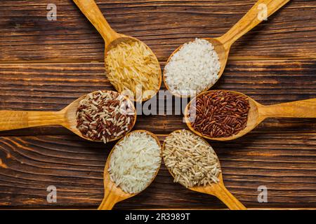 Holzlöffel mit verschiedenen Reissorten auf dem Holztisch Stockfoto