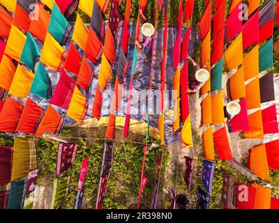 Narayanganj, Dhaka, Bangladesch. 23. Mai 2023, Narayanganj, Dhaka, Bangladesch: Arbeiter hängen Hunderte von farbigen Stoffblättern auf ein Bambusgerüst, um sie in einer Färbefabrik in Narayanganj, Bangladesch, zu trocknen. Der Trocknungsvorgang dauert in der Regel 4 Stunden, wobei jeder Satz aus jeweils 200 Teilen besteht, um bei Temperaturen über 42 °C zu trocknen. Arbeiter verwenden Hüte zum Schutz vor der brennenden Hitze, da sie die bunten Stoffe ständig drehen müssen, damit sie im Sonnenlicht perfekt trocknen. Kredit: ZUMA Press, Inc./Alamy Live News Stockfoto