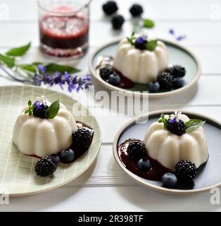 Veganer Zitronen- und Kokosnusspudding mit Brombeersauce, frischen Brombeeren und Heidelbeeren Stockfoto