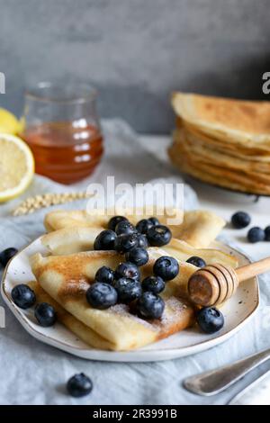 Klassische französische Crepes garniert mit frischen Blaubeeren und Honig Stockfoto