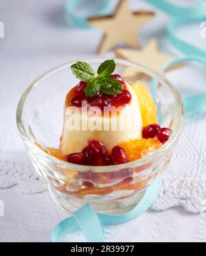 Mousse aus weißer Schokolade mit Granatapfel und Mandarinensoße in einem Glas Stockfoto