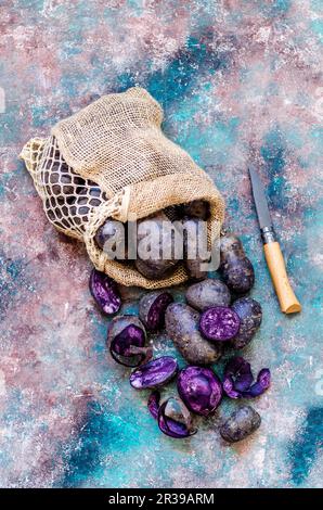 Lila Kartoffeln in einer Tüte und ein Reinigungsmesser Stockfoto