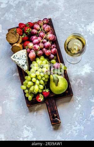 Ein Glas Weißwein und Snacks auf einem Holzbrett Stockfoto