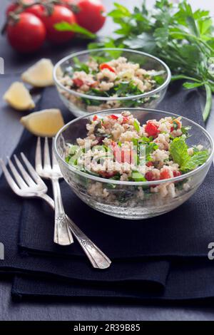 Tabouli-Salat mit Minze, Petersilie, Tomaten und Zitrone in Glasschüsseln Stockfoto