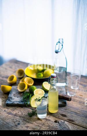 Hausgemachte Zitronen- und Limettenlimonade mit Zutaten auf einem rustikalen Holztisch Stockfoto