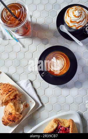 Verschiedene Kaffeegetränke und süßes Gebäck auf einem Tisch in einer Kaffeebar Stockfoto