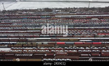 Bahnhof und Güterzugwagen mit SKODA-Wagen und verschiedenen schweren Lasten, Panoramablick aus der Luft, großer Bahnhof-Winterzeit, Farbe Stockfoto