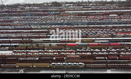 Bahnhof und Güterzugwagen mit SKODA-Wagen und verschiedenen schweren Lasten, Panoramablick aus der Luft, großer Bahnhof-Winterzeit, Farbe Stockfoto