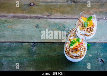 Entgiften Sie griechischen Joghurt, Müsli, pfirsichfarbenen Parfait in Gläsern mit Minzblättern Stockfoto