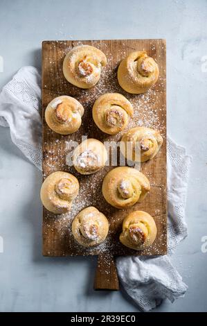 Vegane Hefe-Spiralen mit Puderzucker auf einem Holzbrett (von oben gesehen) Stockfoto