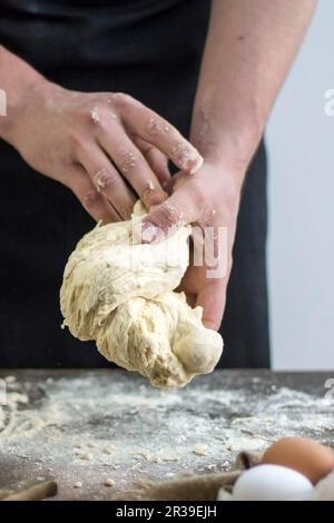 Der Mann in Black Apron hält Raw in den Händen Stockfoto