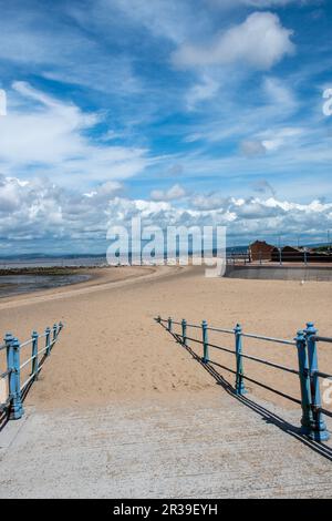 Sandiger Pfad hinunter zum Morecombe Strand mit blauen Geländern Stockfoto