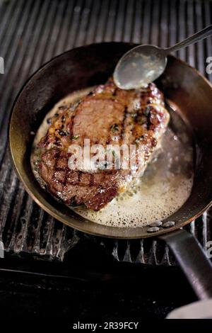 Steak wird mit Butter in einem Topf gebraten Stockfoto