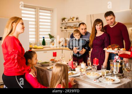 Fröhliche Familie und Freunde essen zu Hause und feiern den Dankeschöntag. Stockfoto